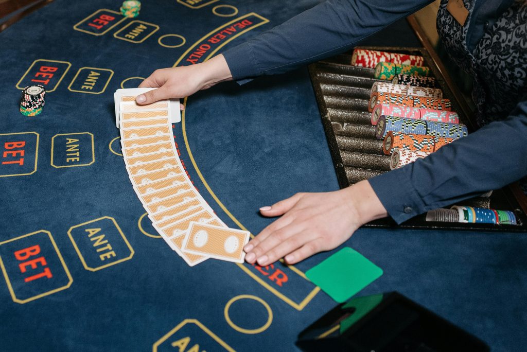 A casino dealer skillfully spreads playing cards on a gaming table, surrounded by colorful poker chips.